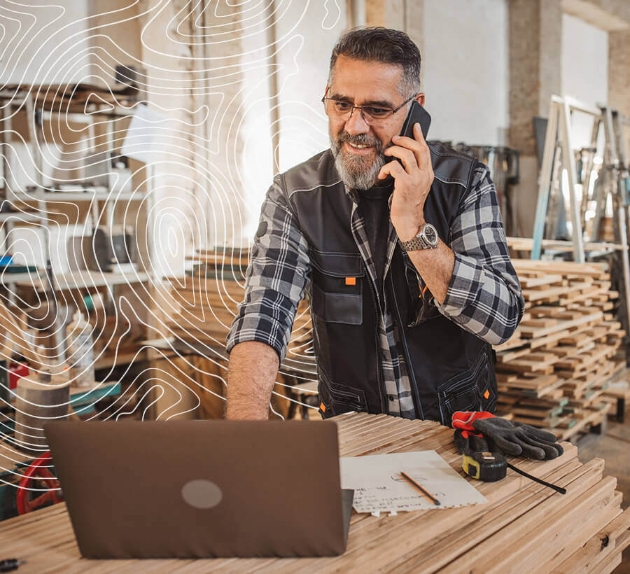 Business man on the phone looking at computer opening up a Red Canoe Business Checking Account